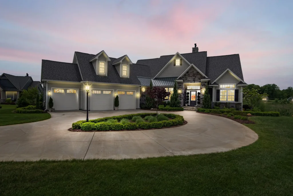 Two-story home with a shingle roof lit up at dusk