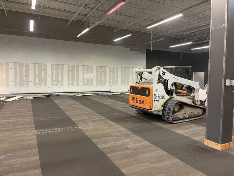 Commercial demolition in Mobile, AL: skid steer pulling up flooring