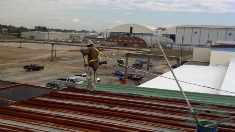 Crew applying rust-inhibiting treatment to a commercial metal roof