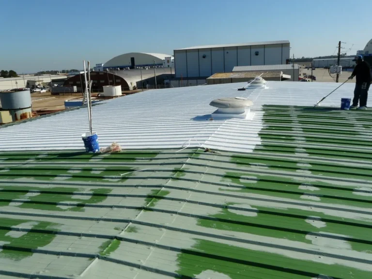 White finish coat being applied over a primed metal roof